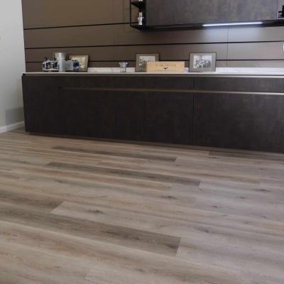 Pavimento vinilico SPC posato all'interno di un salotto moderno a Torino con mobili scuri.